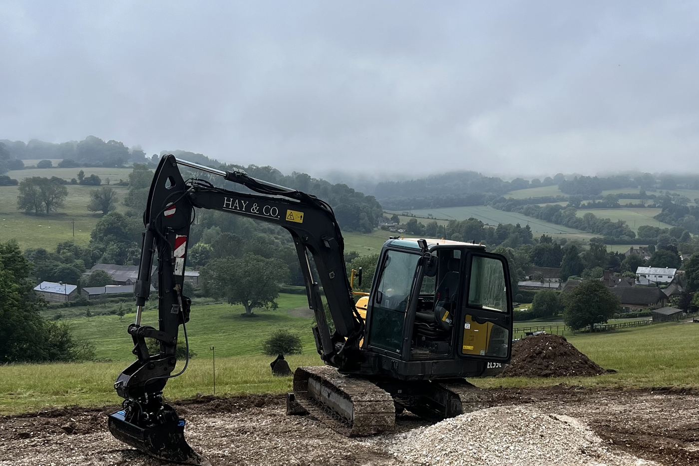 Excavator with operator working in a paddock above the Test Valley