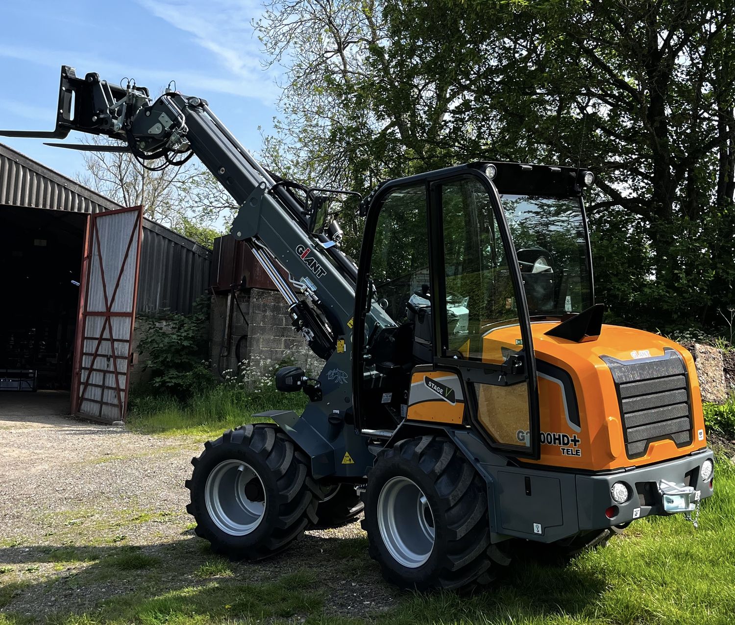 Giant G2700 HD+ pivot-steer telehandler with forks raised at a farm building